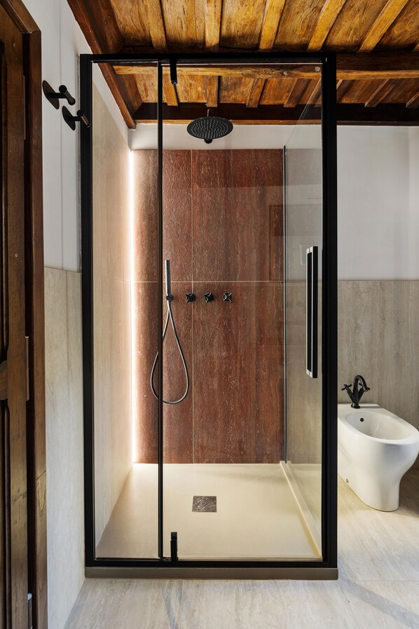 A modern bathroom with a glass-enclosed shower, a white sink, and a wooden ceiling.