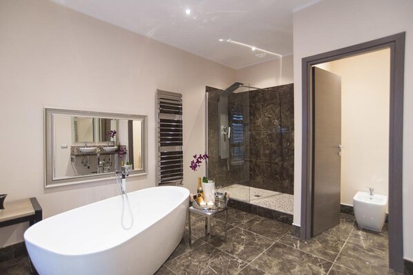 Un baño moderno con una bañera independiente, una ducha con cerramiento de vidrio y un tocador con espejo.