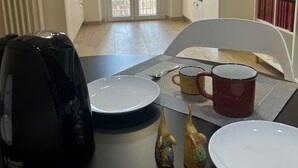 Un coin repas avec une table dressée pour deux personnes, une machine à café et un four à micro-ondes.