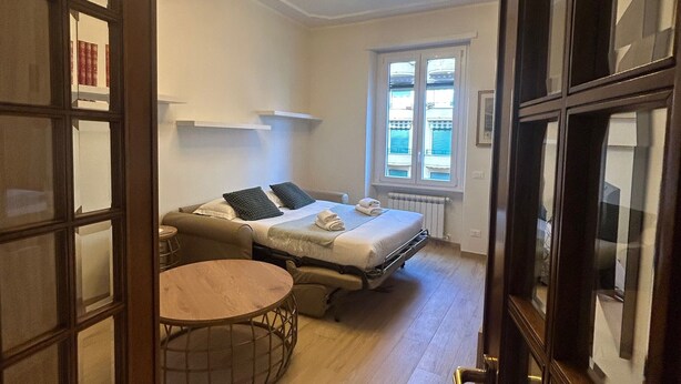 Une chambre à coucher de taille réduite, avec un lit, une table ronde et une fenêtre.