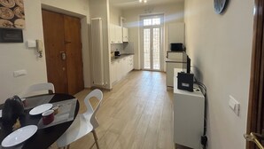 Une cuisine moderne avec des meubles blancs, une table à manger avec des chaises et une horloge au mur.