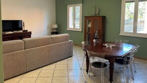 A living room with a sofa, TV, dining table with chairs, and a cabinet. - Casa dei fiori appartamento  6 persone - by Ghor (Rome)