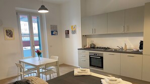 Een modern appartement met een eethoek, keuken en een bed met veel kussens.