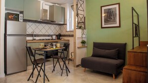 A compact kitchen with a dining area, a sofa, and a staircase. - Ton Ton by Ghor - Studio Apartment, Sleeps 2 (Rome)