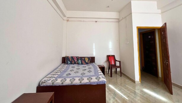 Un dormitorio con cama, una silla, ventilador de techo y puerta.