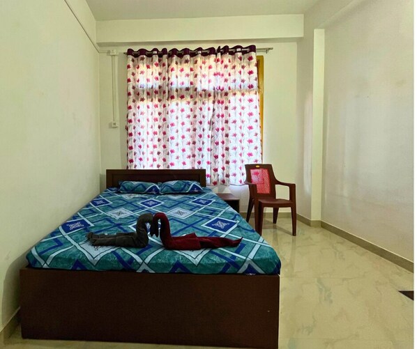 Une chambre à coucher avec un lit, une chaise et une fenêtre avec des rideaux.