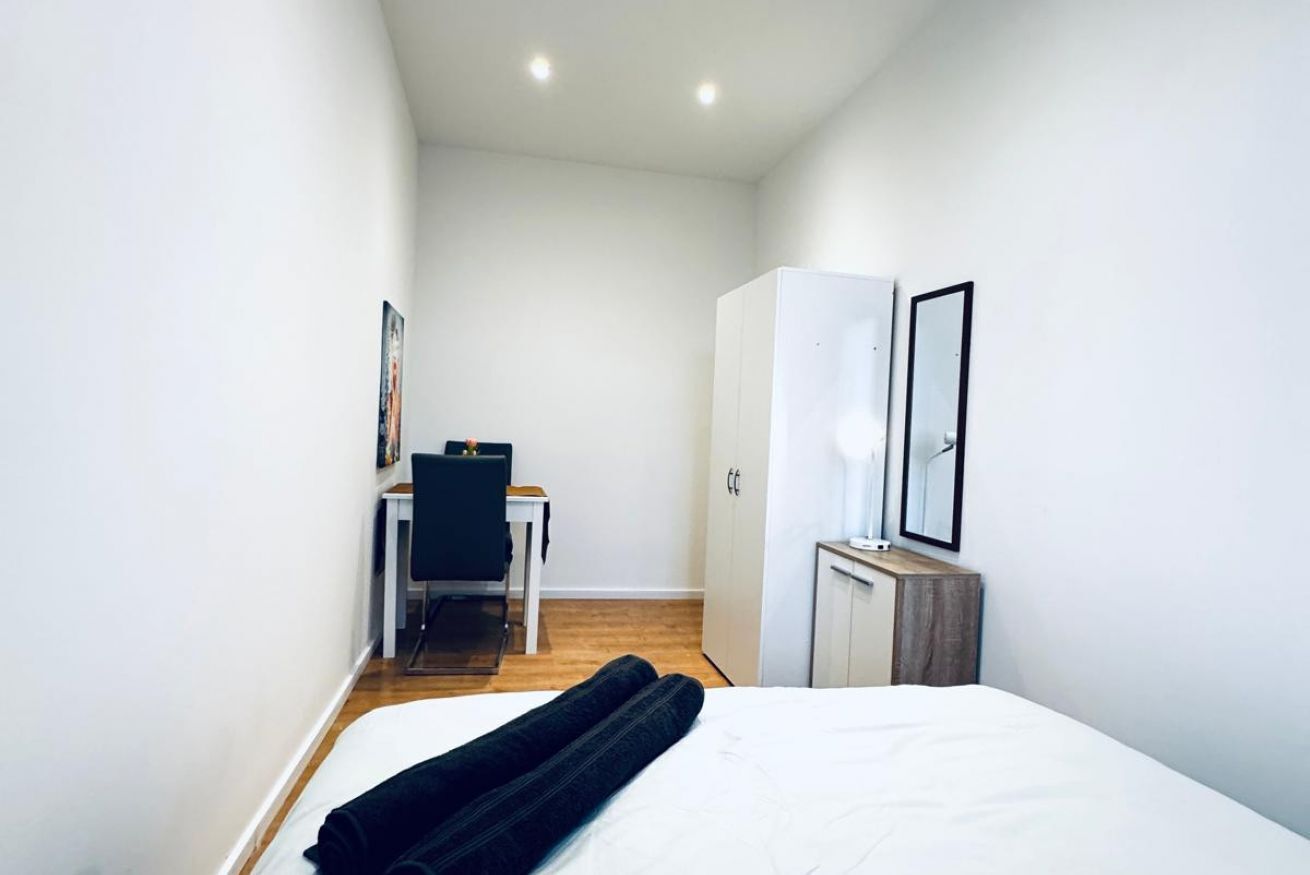 Un dormitorio con una cama, un escritorio, una silla y un armario.