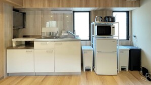 Una cocina compacta equipada con microondas, hervidor y pileta.