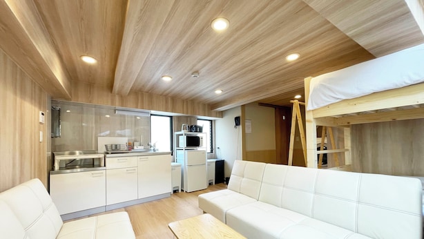 Una sala moderna con un sofá, una mesa de centro y una zona de cocina con electrodomésticos.