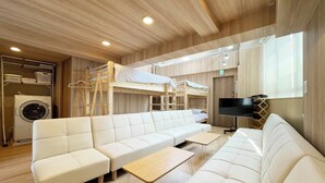 Una habitación moderna y bien iluminada con un conjunto de sofás, un televisor y una lavadora.