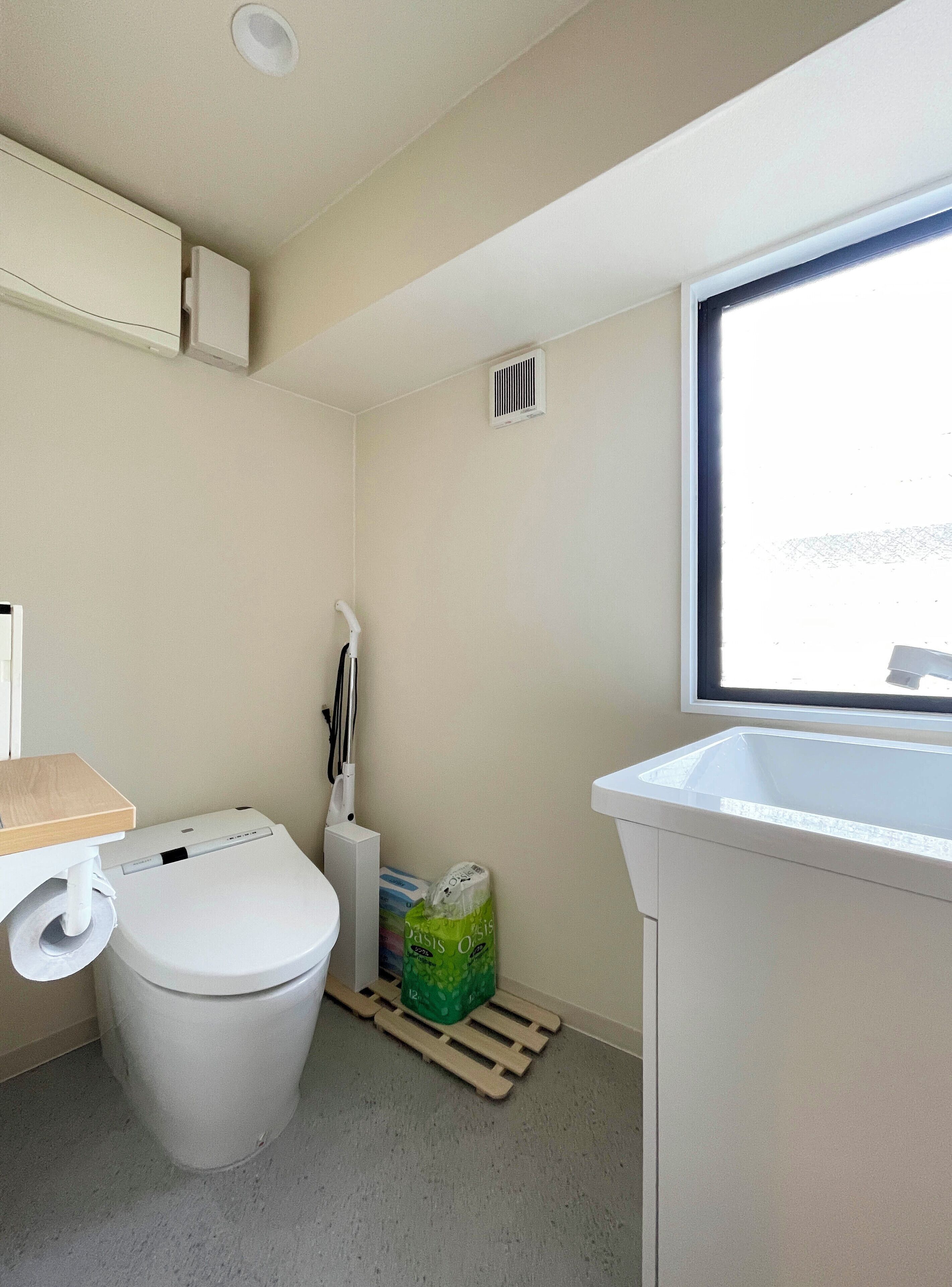 A compact bathroom with a toilet, a sink, and a window.