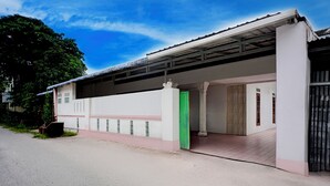 Un edificio con un acceso cubierto, una puerta verde y un suelo de baldosas.