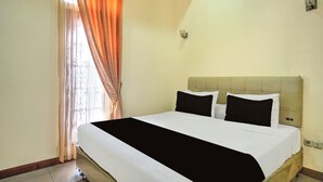 Una habitación de hotel con cama, cortinas y una lámpara.