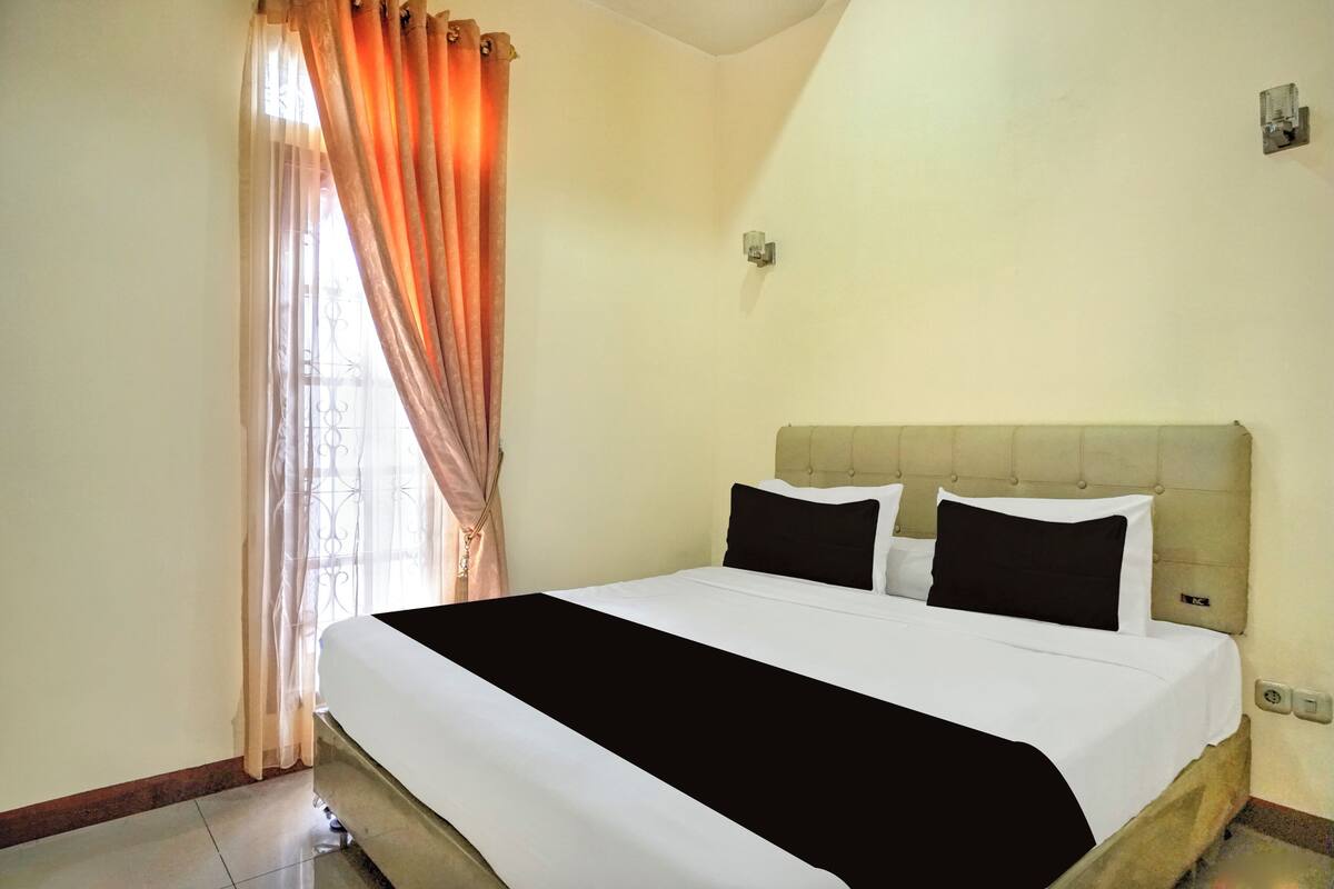 A hotel room with a bed, curtains, and a light fixture.