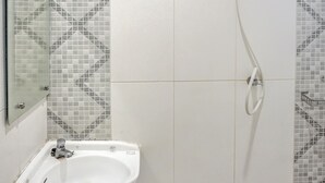Un baño con ducha, lavamanos y espejo.