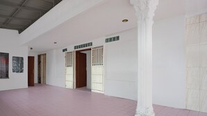 Un interior amplio con techo alto, paredes blancas y suelo de baldosas rosas.
