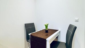 Un pequeño comedor con una mesa, dos sillas y una planta en maceta.