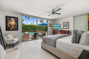 A bedroom with a bed, a chair, a TV, and a view of a swimming pool.