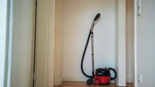 A vacuum cleaner in a hallway with white walls and a wooden floor.