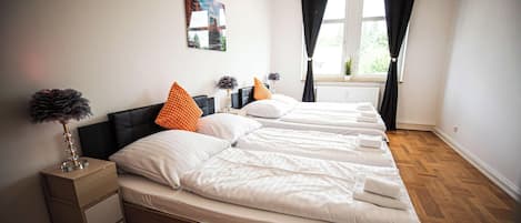 A hotel room with a bed, bedside tables, a window with curtains, and a wall-mounted picture.
