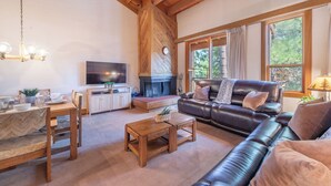 Una sala de estar con chimenea, sofá de cuero, mesa de centro de madera y televisor.