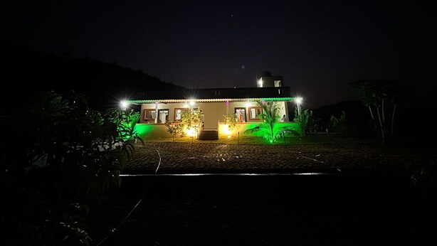 Una casa de dos pisos con techo plano, iluminada por varias luces.
