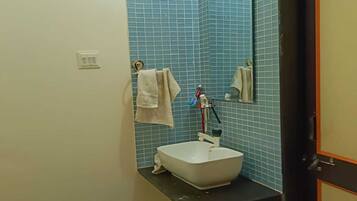 Ein Badezimmer mit einem weißen Waschbecken, blauen Fliesen an der Wand, einem Spiegel und einem Handtuch, das an der Wand hängt.