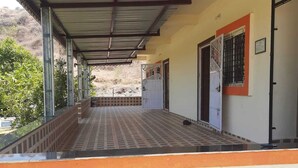 Un espacio exterior techado con suelo de baldosas y vista a un paisaje montañoso.