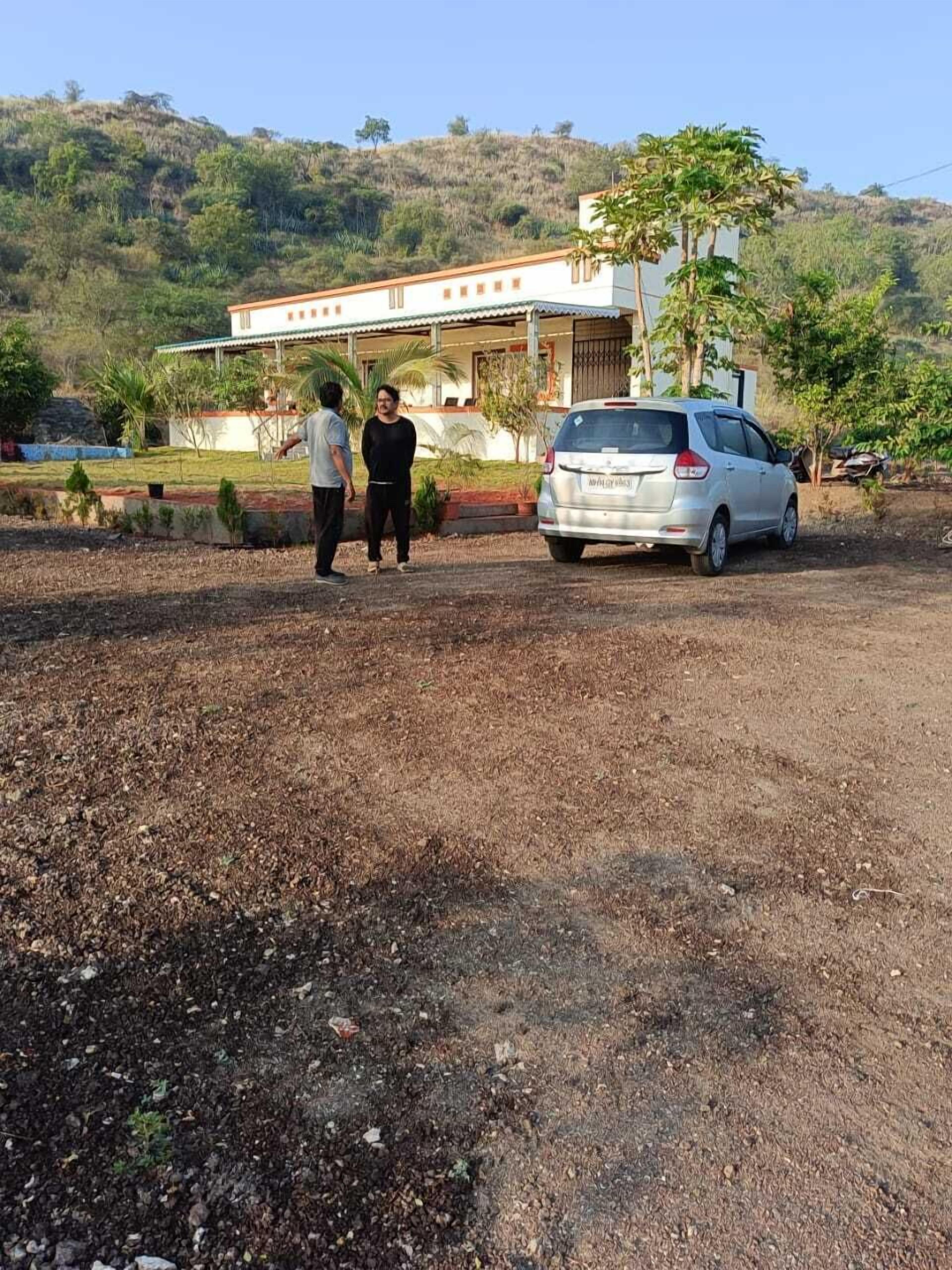 Una casa con pareti bianche e tetto rosso, circondata da un giardino e un paesaggio collinare.
