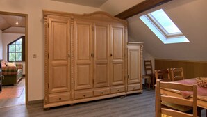 Une pièce spacieuse avec une grande armoire, une table à manger avec des chaises et une lucarne.