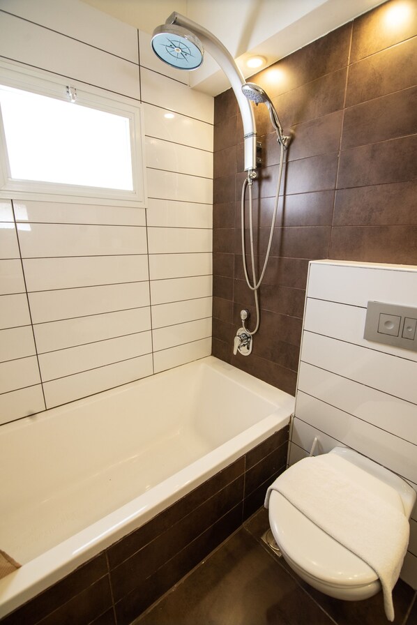 Un baño con bañera, inodoro y ducha.