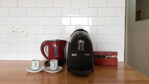 Eine Küche mit weiß gefliestem Fliesenspiegel, einem roten Wasserkocher, einer schwarzen Kaffeemaschine und einer roten Schachtel auf der Arbeitsplatte.