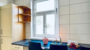 Een keuken met een raam, een vaas, kaarsen en een gedekte tafel voor twee personen.