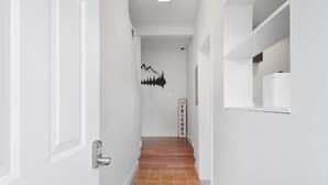 A hallway with white walls, a tiled floor, and a staircase leading to another room.