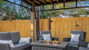 An outdoor seating area with a fire feature, wicker furniture, and a wooden fence.
