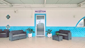 Ein Empfangsbereich mit einem Schild, zwei Sofas und Topfpflanzen.