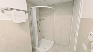 Eine Eckdusche mit Glastür, ein Handtuchhalter und eine Toilette.