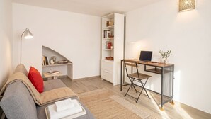 Uma sala de estar moderna com um sofá, uma escrivaninha, uma estante e um abajur.