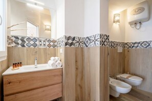 A modern bathroom with a wooden vanity, a mirror, a sink, two bidets, and patterned tiles. - Gabbiano 2 - Sea Loft  (Bari)