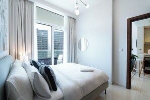 A modern hotel room with a large bed, a bedside table, a mirror, and a view of the city through a large window. - KeyRock - Premium Reva Stay with Pool (Dubai)