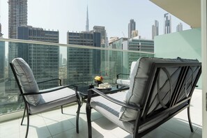 A balcony with two chairs, a small table, and a tray with a cup and a fruit. - KeyRock - Premium Reva Stay with Pool (Dubai)