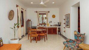 A spacious kitchen with wooden cabinets, a dining table with chairs, a ceiling fan, and a potted plant. - Babu Villas - Family Apartment with Sea View "Familia" (Jambiani)