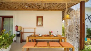 A wooden dining table with orange cushions, a small window, and a water dispenser. - Babu Villas - Family Apartment with Sea View "Familia" (Jambiani)