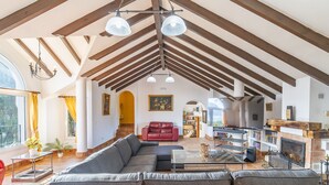 A spacious living room with a large sectional sofa, a fireplace, and a bookshelf.