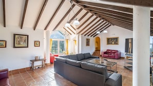 A spacious living area with a large sectional sofa, a red leather couch, and a TV stand.