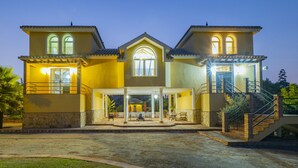 A two-story house with a covered patio, a staircase, and a pool area.