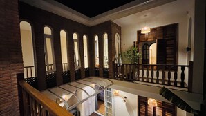A multi-level interior with a balcony, arched windows, and wooden railings.