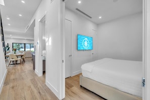 Quarto de hotel moderno com uma cama, televisão na parede e vista para o exterior.