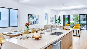 Una cocina moderna con una isla grande, comedor y sillas amarillas.