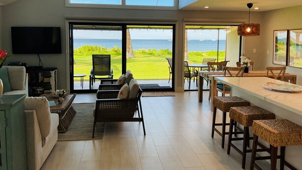 A spacious living area with a large window overlooking a golf course and the sea. - Ma'alaea Surf, Unit A4-2 BR Ground Floor Beachfront Condo, AC, Wi-Fi, Pool (Kihei)